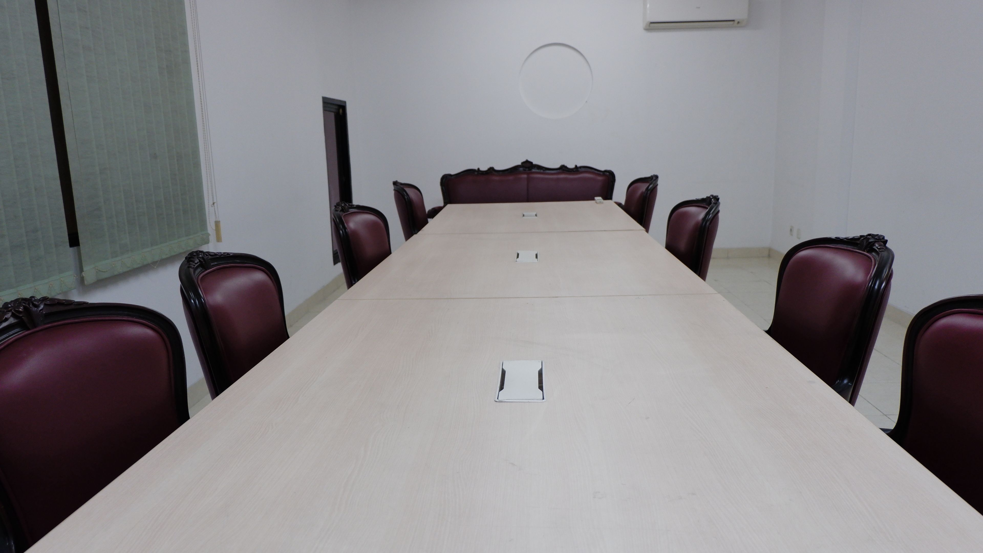 Un salón de conferencias con una mesa larga, ocho sillas y una pizarra en la pared.