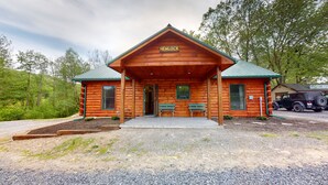 A wooden cabin named "HEMLOCK" with a porch, two windows, and a bench.