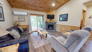 A cozy living room with a stone fireplace, wooden ceiling, and comfortable seating.