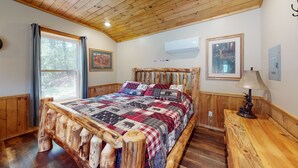 A rustic bedroom with a wooden bed frame, a quilt, and a nightstand with a lamp. - Mountain View, Pine Creek, PA Grand Canyon (Gaines)