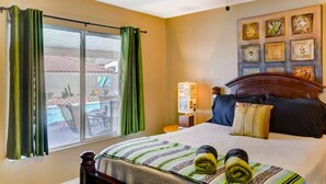 A hotel room with a bed, a nightstand, a lamp, a window with curtains, and a view of the outside.