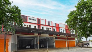 A building with a sign reading "METRO" and a covered parking area with multiple garage doors. - Hotel O Penginapan Metro Parepare (Makassar)