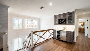 A spacious kitchen with wooden floors, white walls, and a view of the backyard through large windows. - Harborside by AvantStay | Expansive Destin Retreat (Destin)