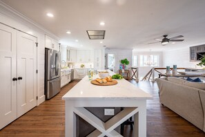Une cuisine moderne avec des meubles blancs, un îlot central et un coin repas comprenant un canapé et une table.