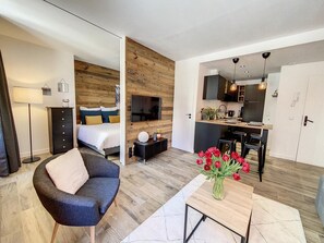 Een moderne hotelkamer met een bed, een bureau, een stoel, een televisie en een eethoek.