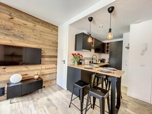 Een moderne keuken met een houten accentmuur, een centraal eiland met barstoelen en hanglampen.
