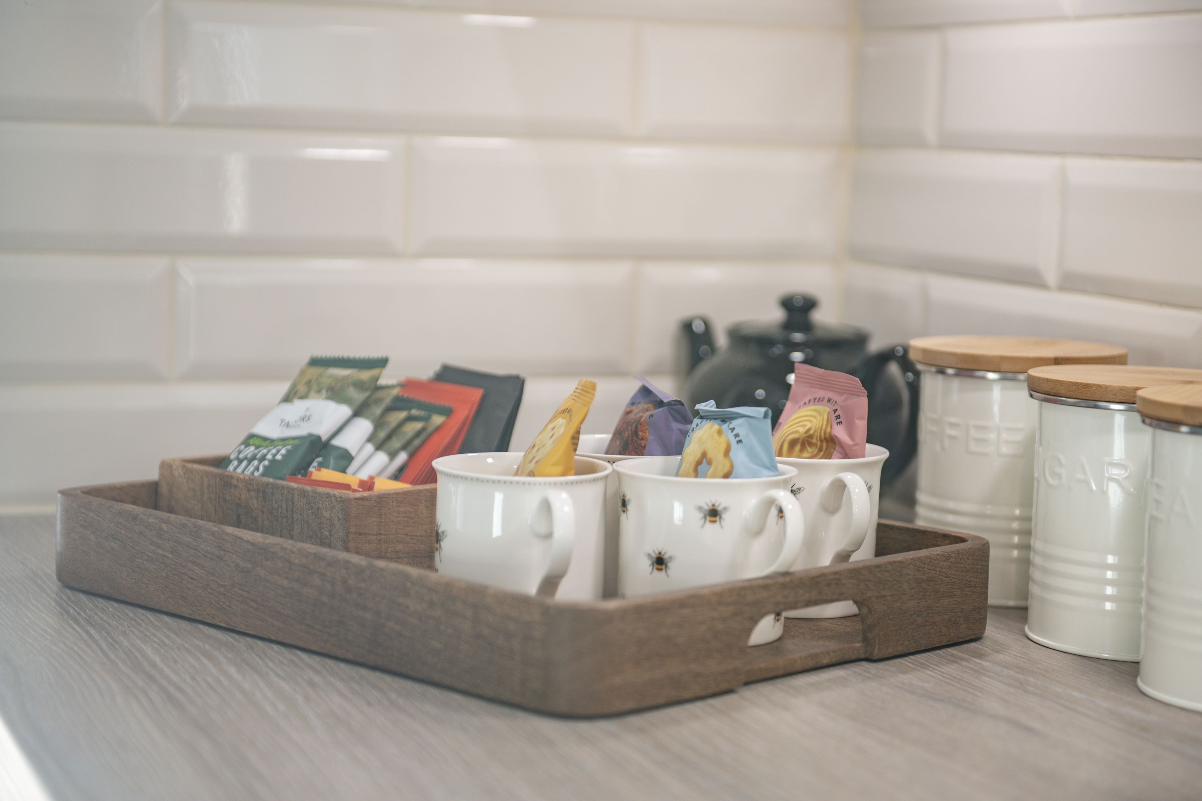 A tray with mugs and tea bags on a kitchen counter.