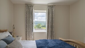 Un dormitorio con cama, mesita de noche, lámpara y ventana con cortinas.