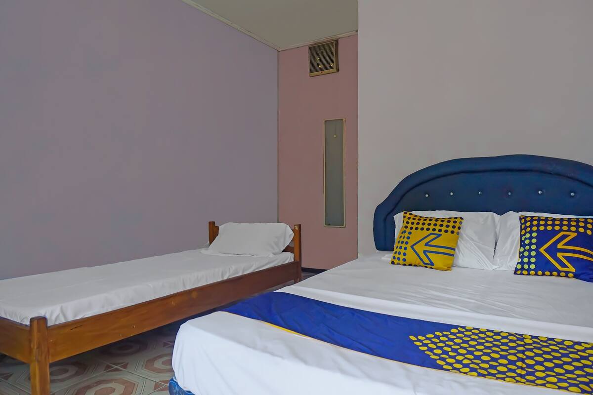 A bedroom with two single beds, a blue headboard, and patterned pillows.