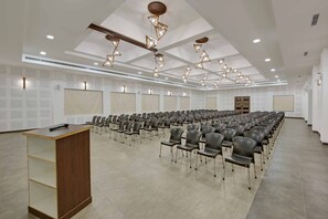 A conference room with rows of chairs, a podium, and modern lighting fixtures. - The Maharana Bagh (Udaipur)