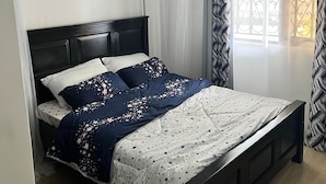 Un dormitorio con una cama, dosel y ventana con cortinas.