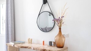 Een houten bureau met een spiegel, een vaas met gedroogde bloemen en enkele persoonlijke spullen.