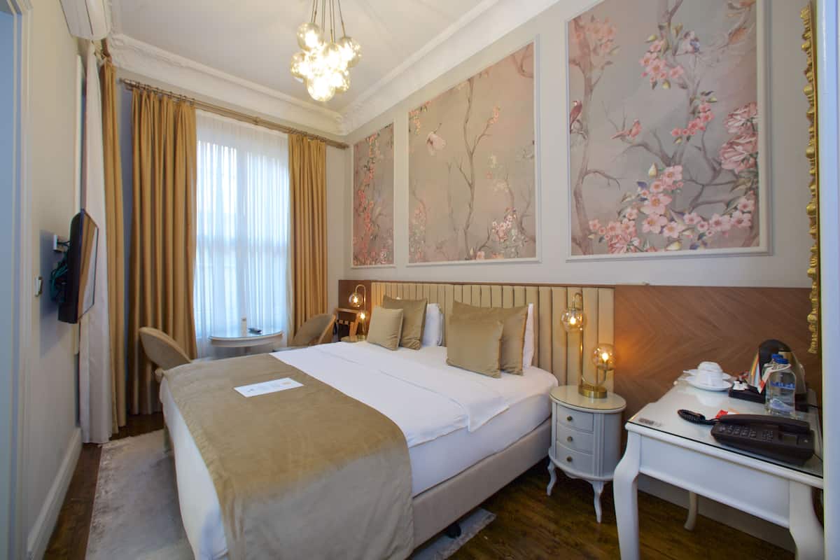 A hotel room with a bed, bedside tables, a desk, and a chair.