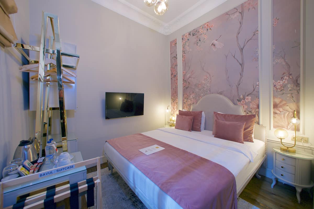 A neatly arranged hotel room with a bed, bedside table, and a mirror.