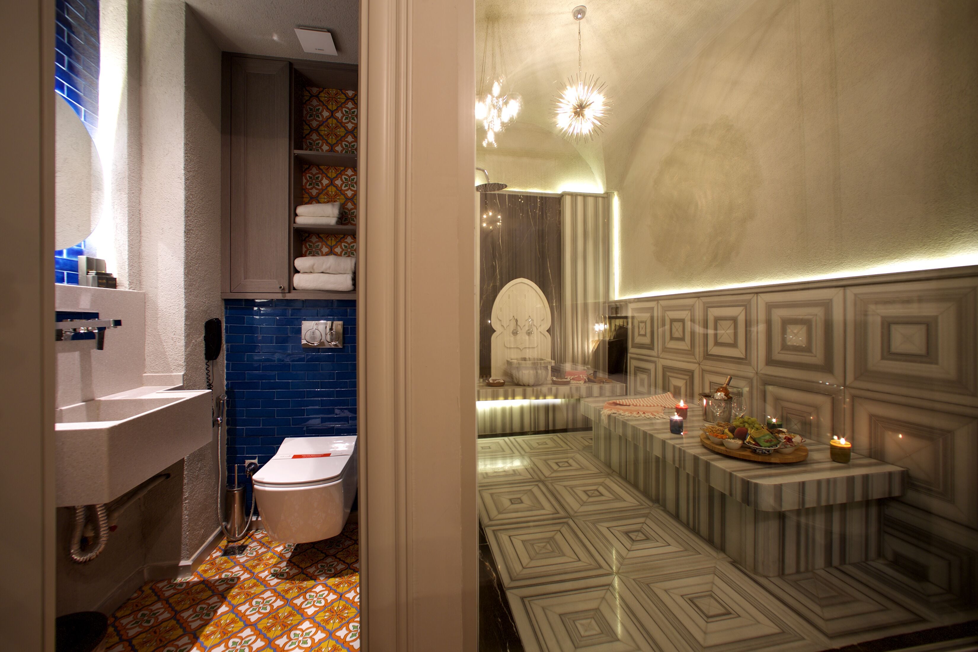Un baño con un lavamanos blanco, paredes con azulejos azules y un suelo estampado.