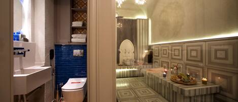 Un baño con un lavamanos blanco, paredes con azulejos azules y un suelo estampado.