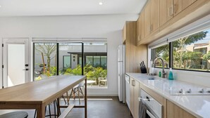 Une cuisine moderne dotée d’une grande fenêtre, de meubles en bois et d’un coin repas avec une table et des chaises.