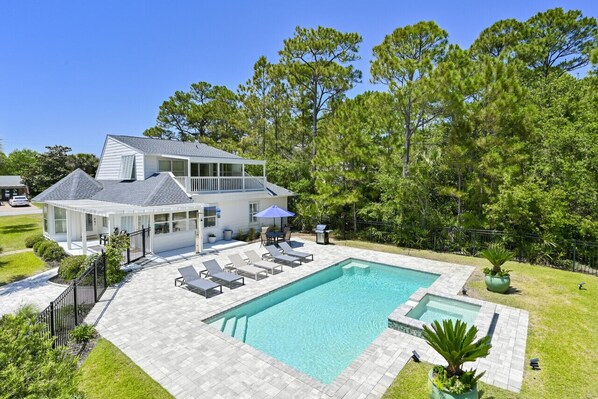 A two-story house with a swimming pool, outdoor seating, and a fenced yard.