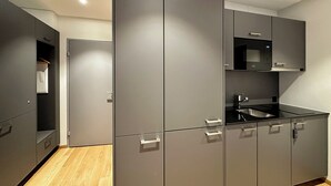 Une cuisine moderne avec des meubles gris, un four à micro-ondes encastré et un évier en acier inoxydable.
