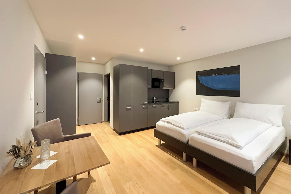 Un dormitorio moderno con una cama doble, un escritorio pequeño y una kitchenette.
