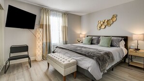 A modern bedroom with a large bed, a TV mounted on the wall, a bedside table with a lamp, and a decorative wall piece. - Dreamy Vegas Strip area condo (Las Vegas)