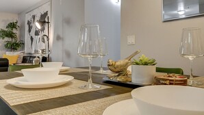 A dining area with a wooden table, white plates, and clear wine glasses. - Dreamy Vegas Strip area condo (Las Vegas)