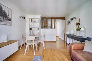 Uma sala de estar moderna com uma mesa de jantar de vidro, cadeiras brancas, um sofá de couro e uma estante.