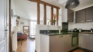 A modern kitchen with a central island, stainless steel appliances, and a wooden ceiling beam. - Magnificent apartment ideally located in Paris (Paris)