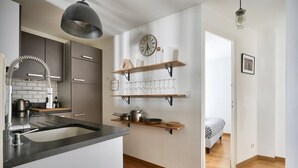 A modern kitchen with a central island, stainless steel appliances, and wooden shelves above the counter. - Magnificent apartment ideally located in Paris (Paris)