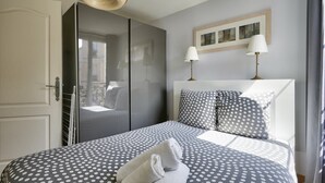 A bedroom with a bed, two bedside lamps, a wardrobe, and a window with curtains. - Magnificent apartment ideally located in Paris (Paris)