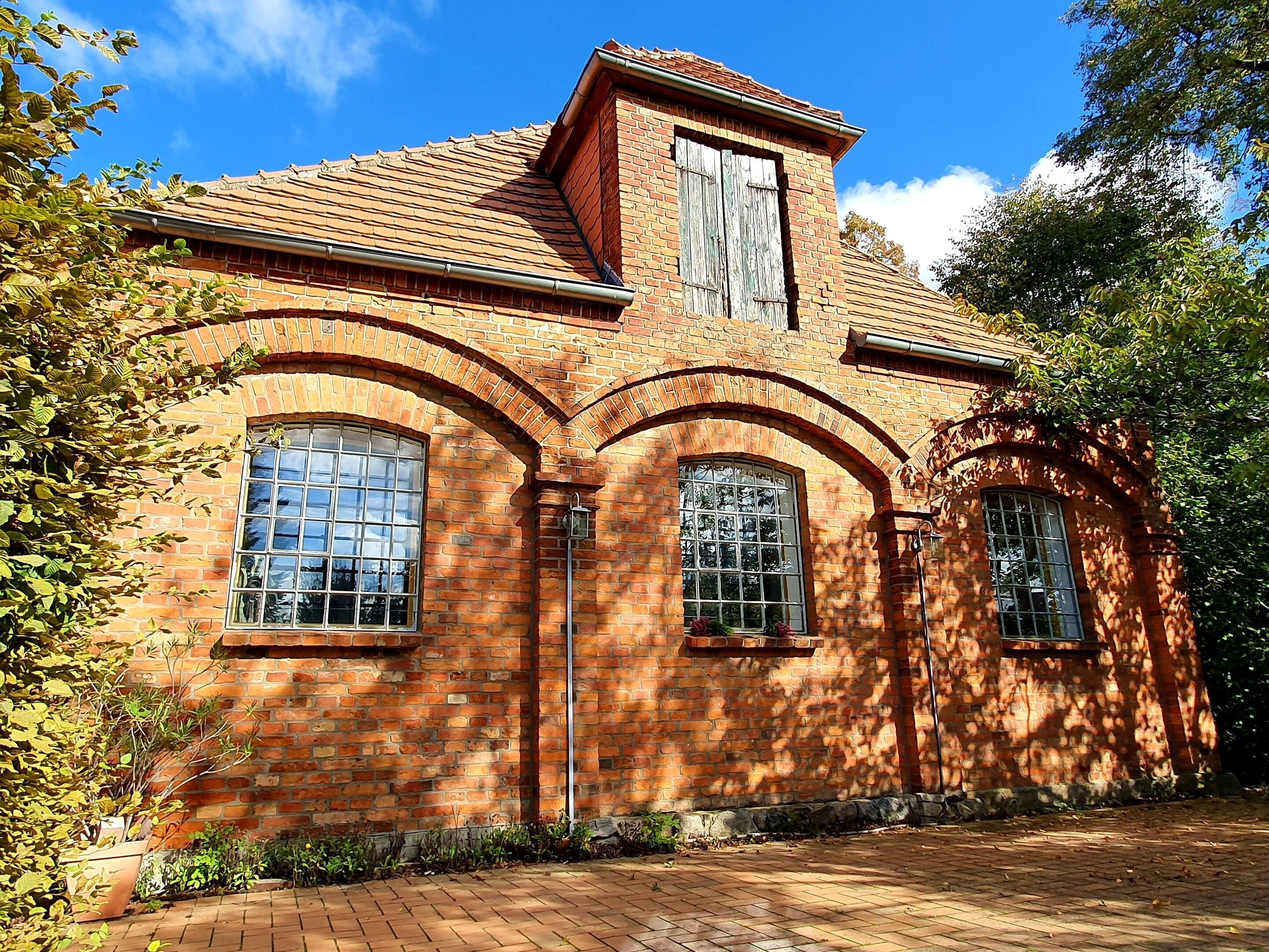 A brick building with arched windows and a central chimney.