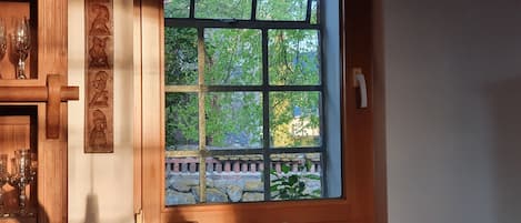 A kitchen with a window, a coffee maker, and a mug on the counter.