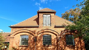 Ein Backsteinhaus mit Satteldach, Rundbogenfenstern und einem zentralen Schornstein.