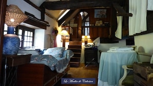 Una camera accogliente con soffitto in legno, un letto con copriletto floreale, un tavolo con tovaglia bianca e una lampada.