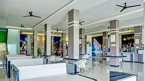 Un hall d’entrée spacieux doté de plusieurs coins salon, de ventilateurs de plafond et d’un bar à café.