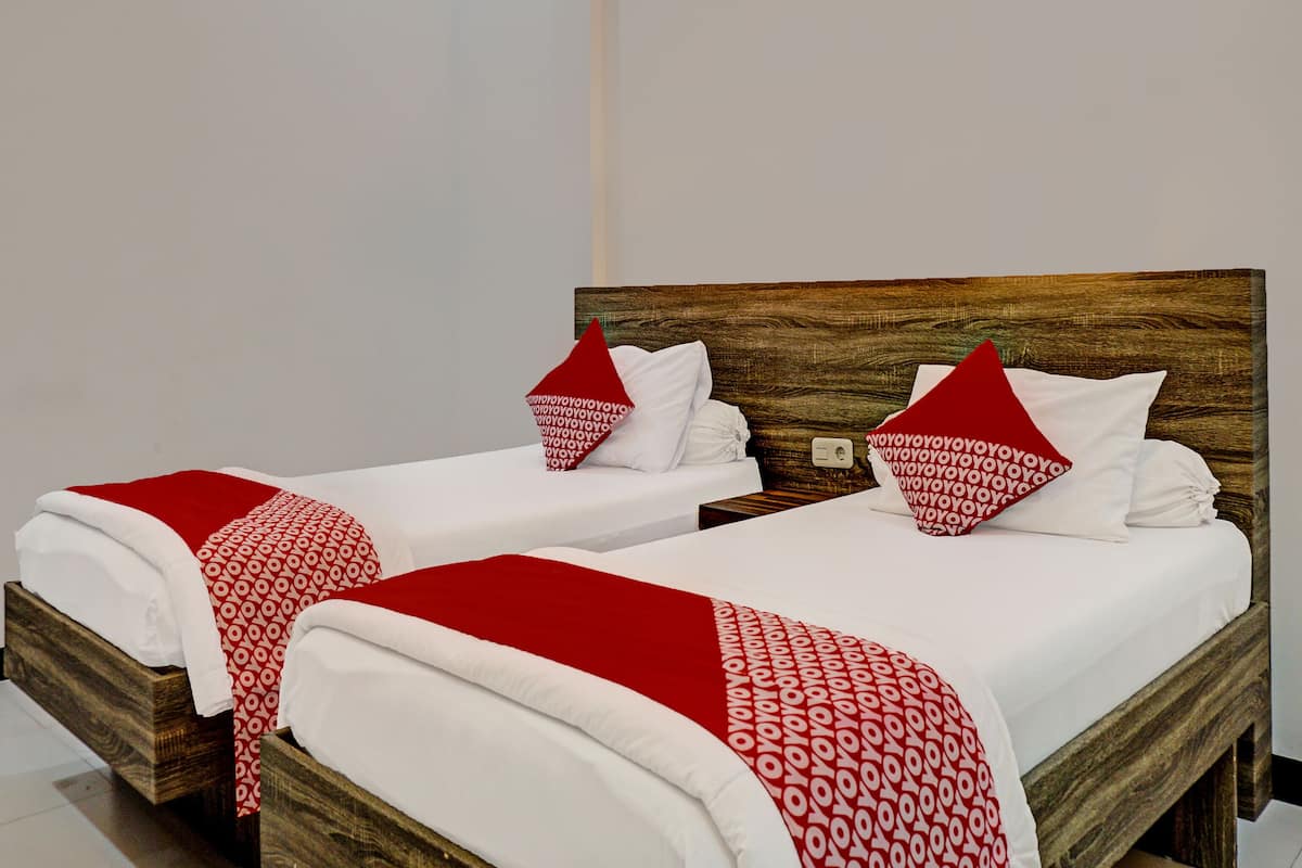 Ein Hotelzimmer mit zwei Betten, jeweils mit einem Holz-Kopfteil und weißer Bettwäsche.