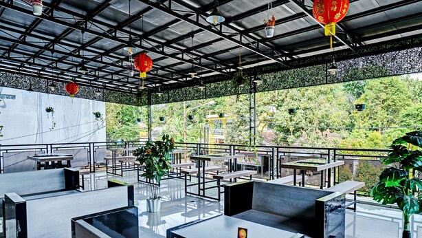 Un espace extérieur aménagé avec des tables et des chaises, des lanternes suspendues et des plantes en pot.