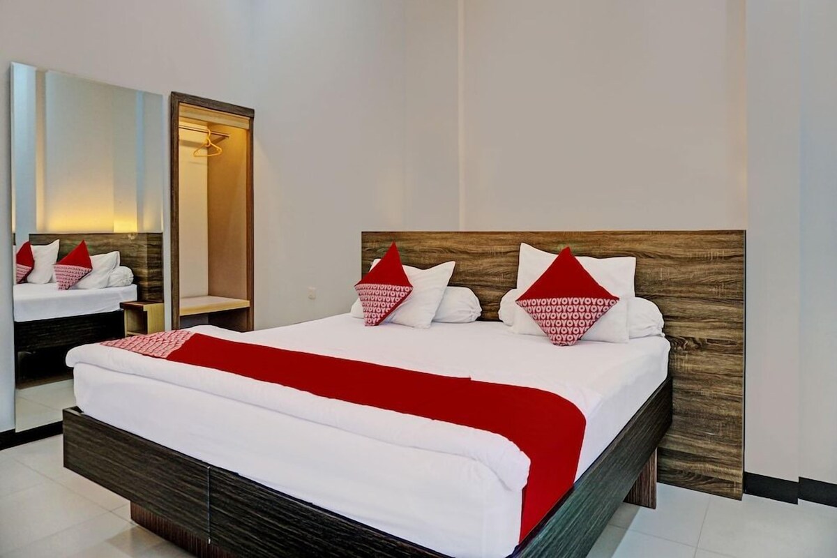 Una habitación de hotel con una cama grande, un cabecero de madera, un espejo y un armario.