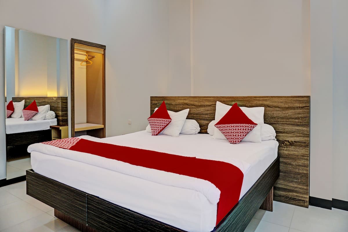 Ein modernes Hotelzimmer mit einem großen Bett, einem Holz-Kopfteil und einem Spiegel.