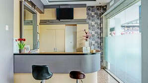 Un espace d’accueil doté d’un comptoir incurvé, de deux tabourets de bar, d’un téléviseur à écran plat fixé au mur et d’un vase décoratif contenant des fleurs.