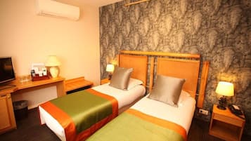 Camera d'albergo con due letti, una scrivania, una televisione e un muro con motivo in pietra.