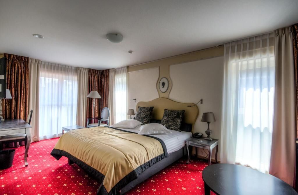 Una habitación de hotel con una cama grande, un escritorio, una silla y una mesita.