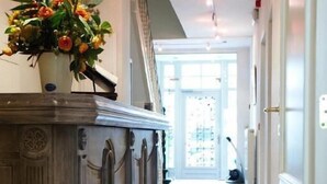 Un pasillo con una columna de mármol, una planta en maceta y una escalera que conduce a una habitación luminosa.