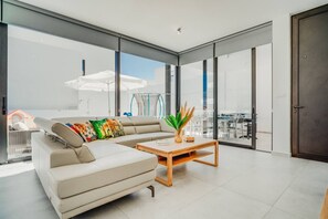 Una sala de estar moderna con sofá, mesa de centro y ventanas amplias.