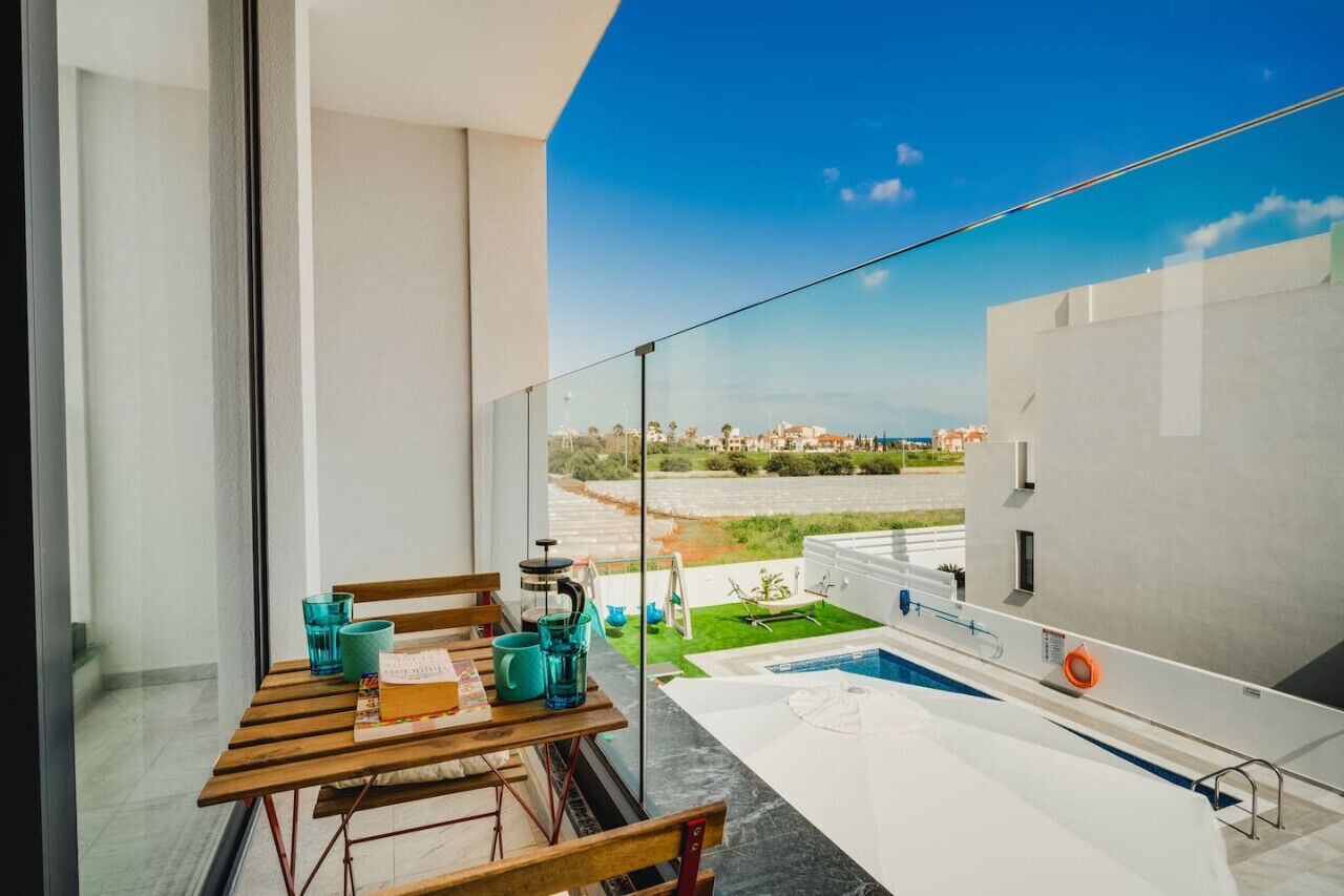 A balcony with a view of a swimming pool and a cityscape.