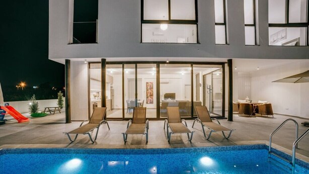 A modern building with a swimming pool, lounge chairs, and a slide. - SunnyVillas:2BR+Ensuite CozyVilla*Private Pool*AL9 (Paralimni)