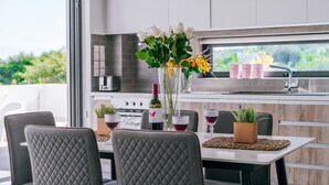 A modern kitchen with a dining table, chairs, and a vase of flowers. - SunnyVillas:2BR+Ensuite CozyVilla*Private Pool*AL9 (Paralimni)