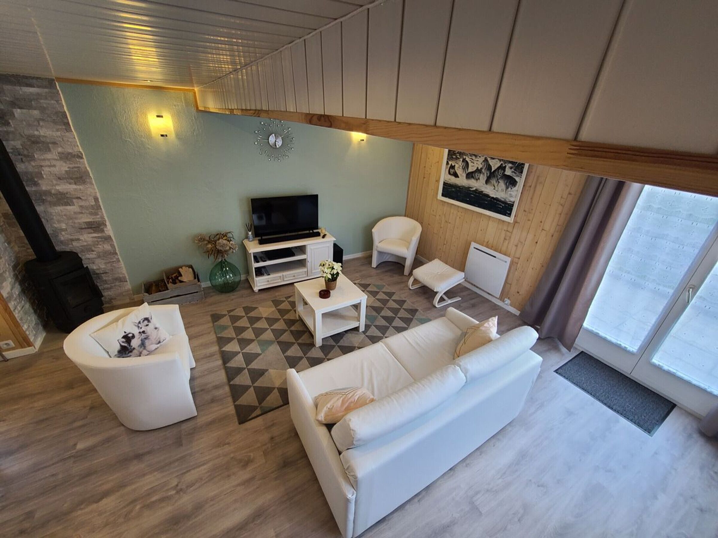Ein modernes Wohnzimmer mit Sofa, Sessel, Couchtisch und einem Fernseher auf einer Holzkommode.