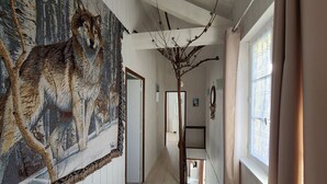 A hallway with a large wolf painting on the left, a tree branch decoration, and a window on the right. - Charming Cottage in Taintrux: Hiking, Skiing, Close to Saint-Dié & Alsace Attractions (Taintrux)
