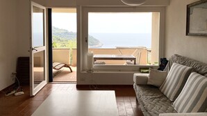 Ein Zimmer mit Meerblick, ein Balkon mit Tisch und Stühlen, eine Sitzecke und eine Hängelampe.